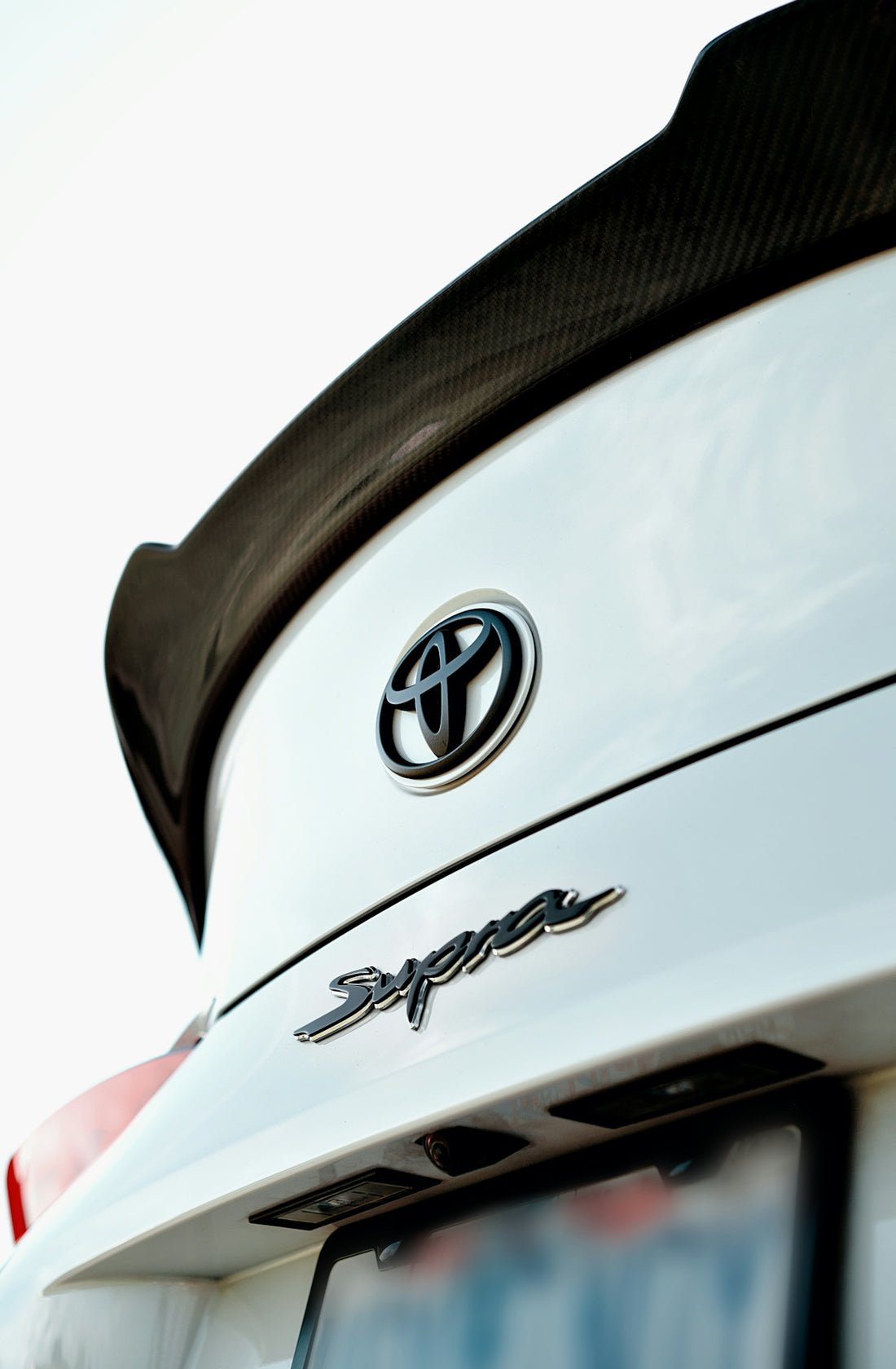 A white toyota supra features a sleek spoiler.